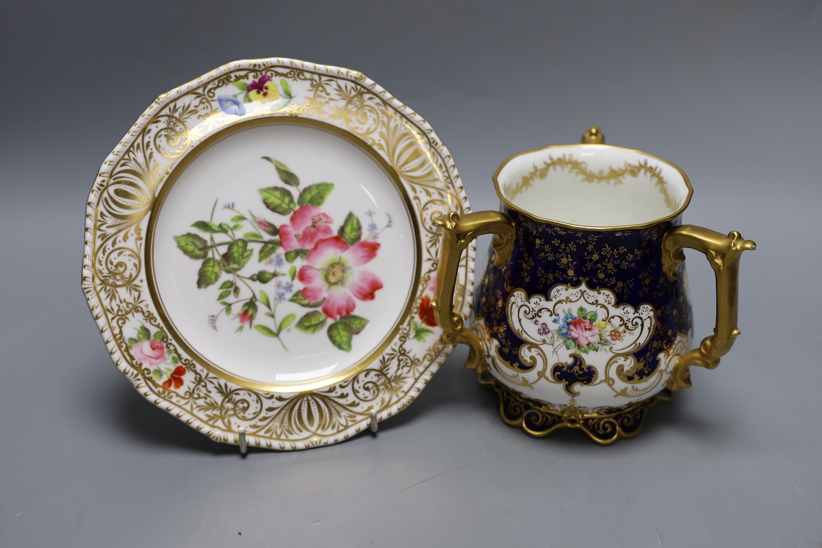 A Derby King Street plate by Harry Sampson Hancock monogrammed verso 'II' red S and H mark and a Royal Crown Derby three handled loving cups